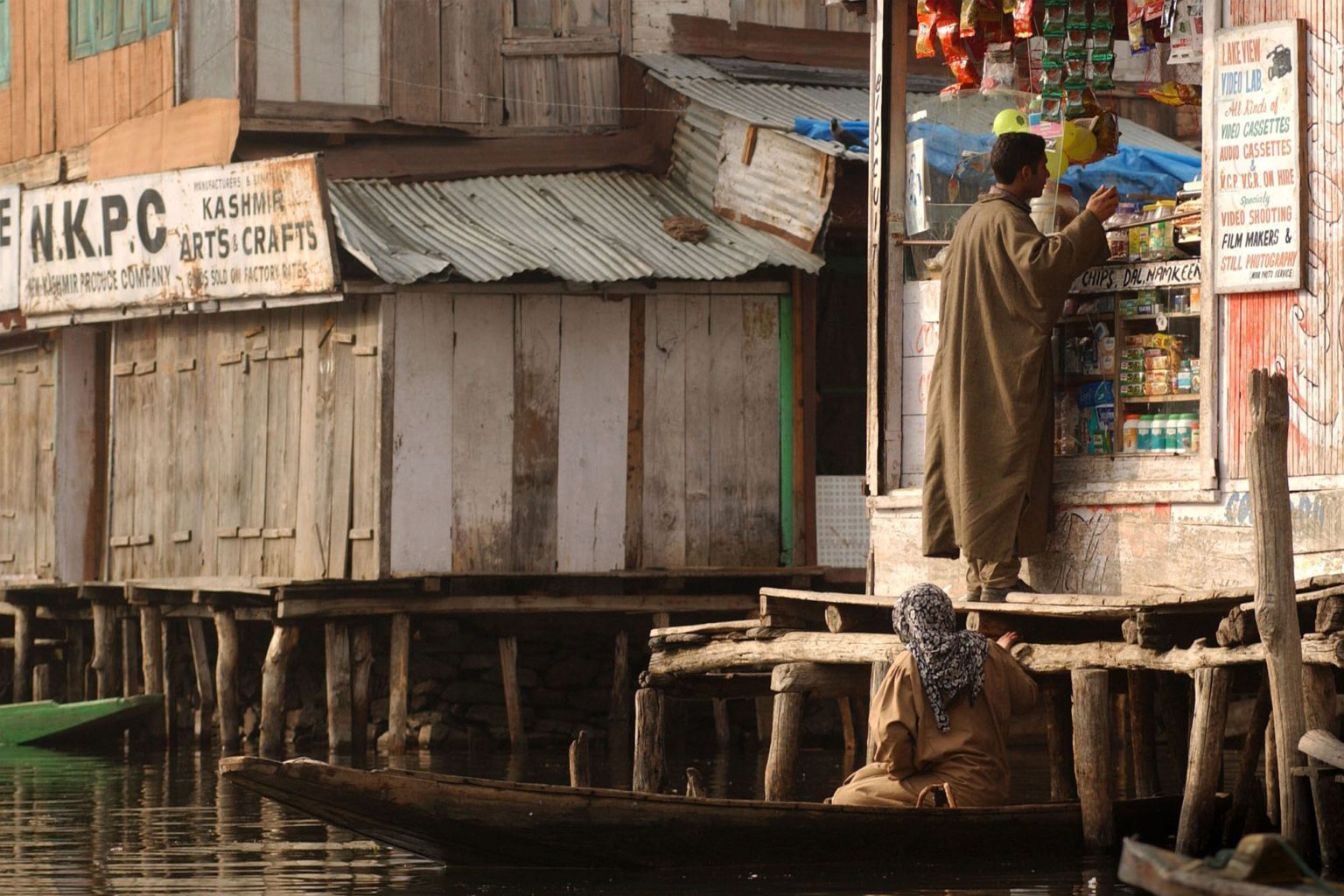 A woman pulls up her boat to pick up some items at a shop on Lake Dal, Srinagar (2002).