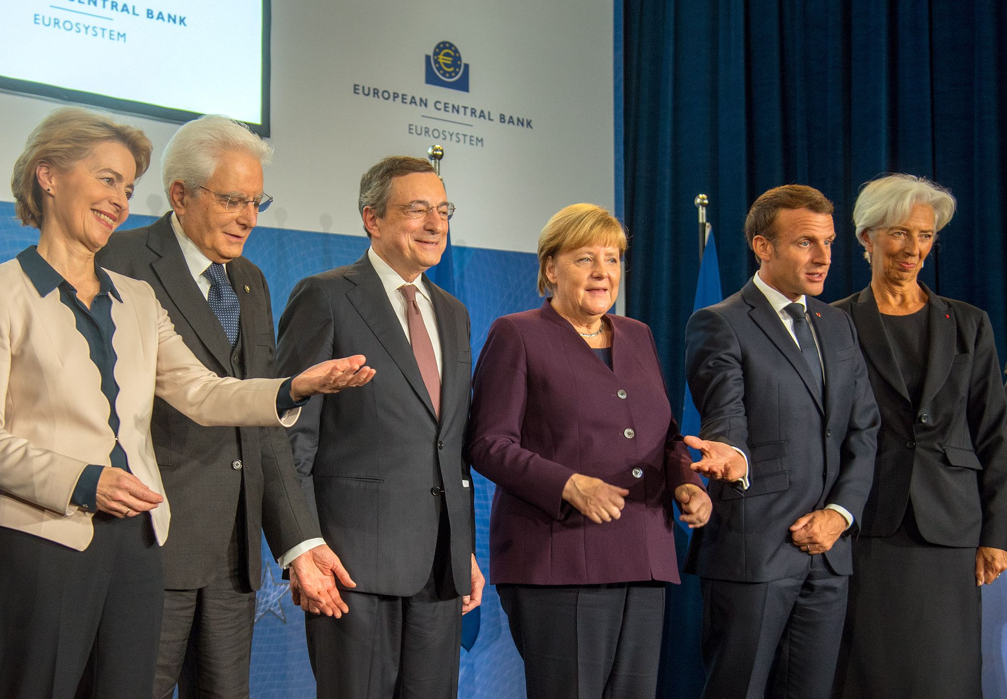 Mario Draghi, standing with Angela Merkel and Emmanuel Macron, during his farewell ceremony, 28 October 2019, in Frankfurt am Main, Germany.