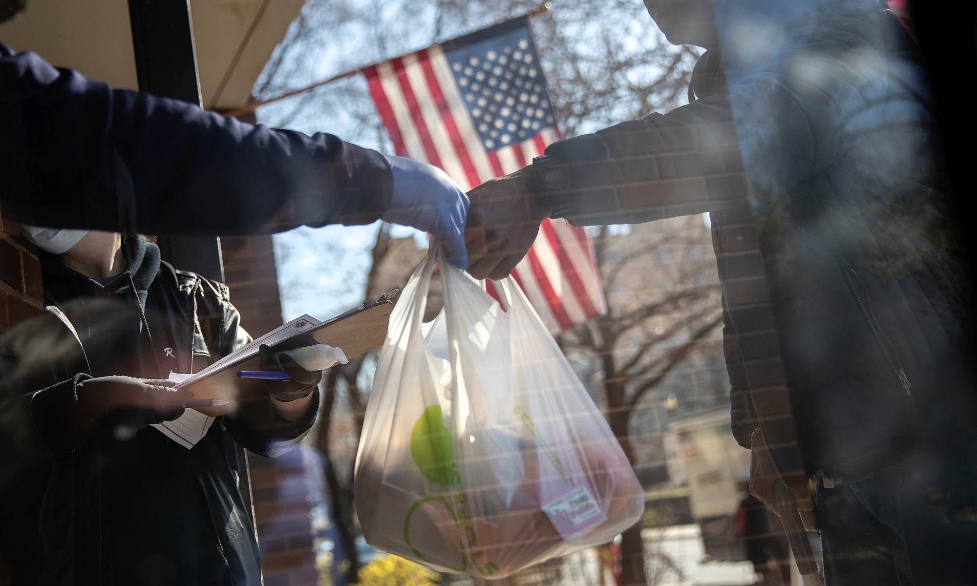Residents receive bags of free food at the WestCop community center on 18 March 2020 in New Rochelle, New York.
