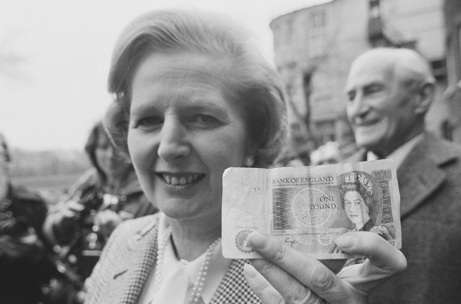 Margaret Thatcher holds a Bank of England £1 note aloft, 27 April 1979.