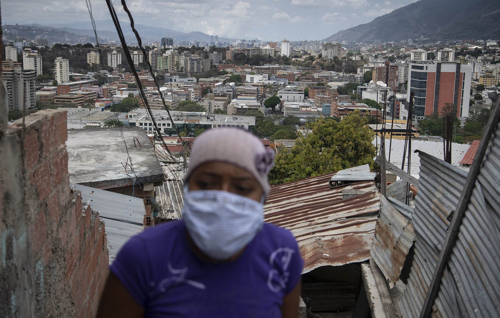 A woman wearing a protective mask delivers food in Caracas, Venezuela, on 23 March 2020.