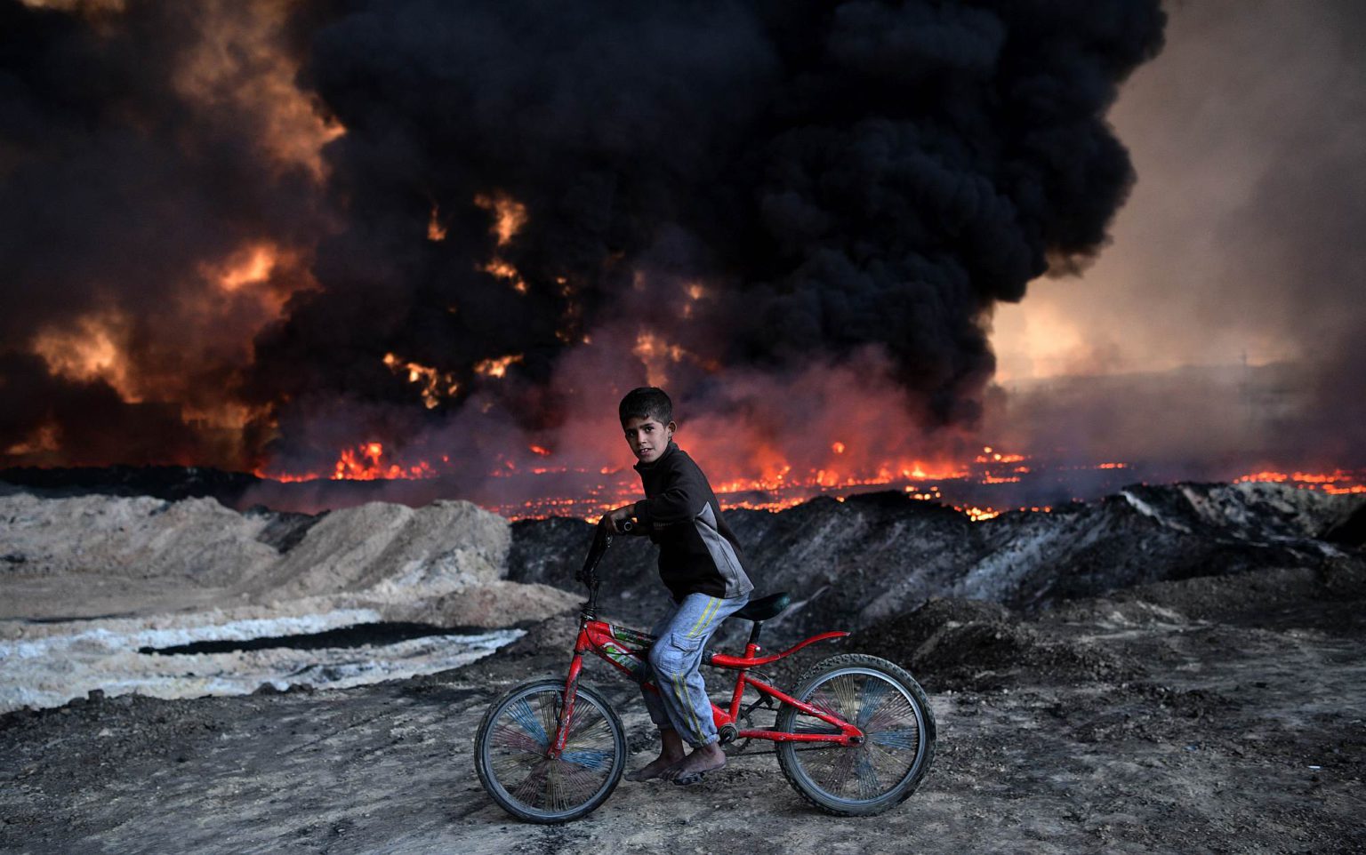 A boy passes an oil field set on fire by retreating ISIS fighters in Qayyarah, Iraq, on 21 October 2016.