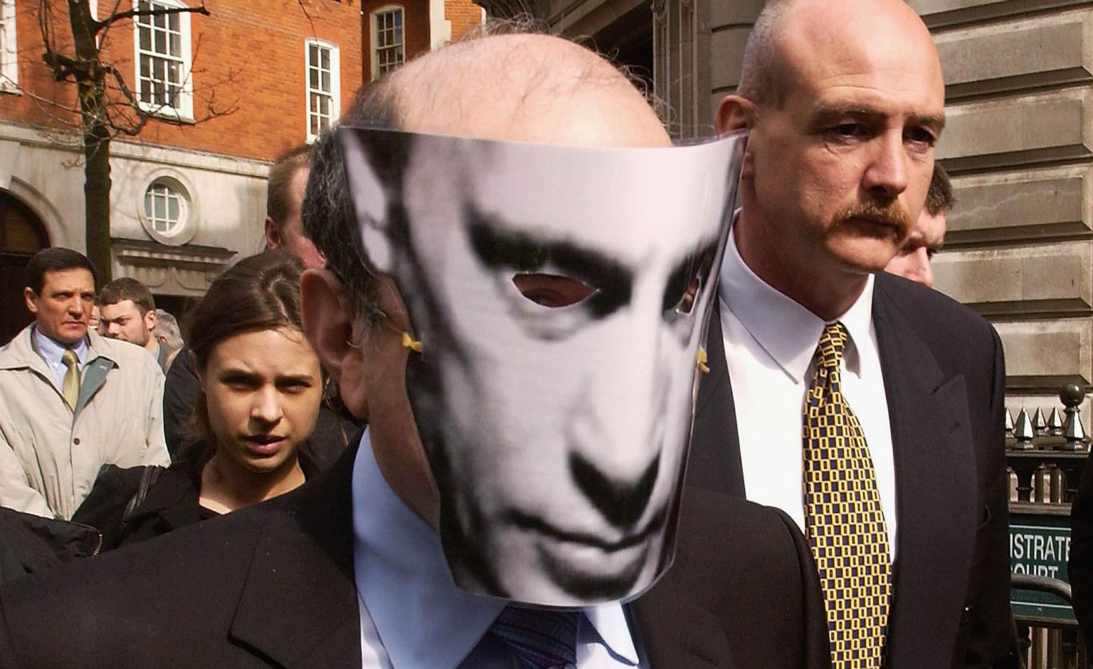 Boris Berezovsky wears a Putin mask as he leaves Bow Street Magistrates Court (2 April 2003), after Russian officials sought his extradition on fraud charges.