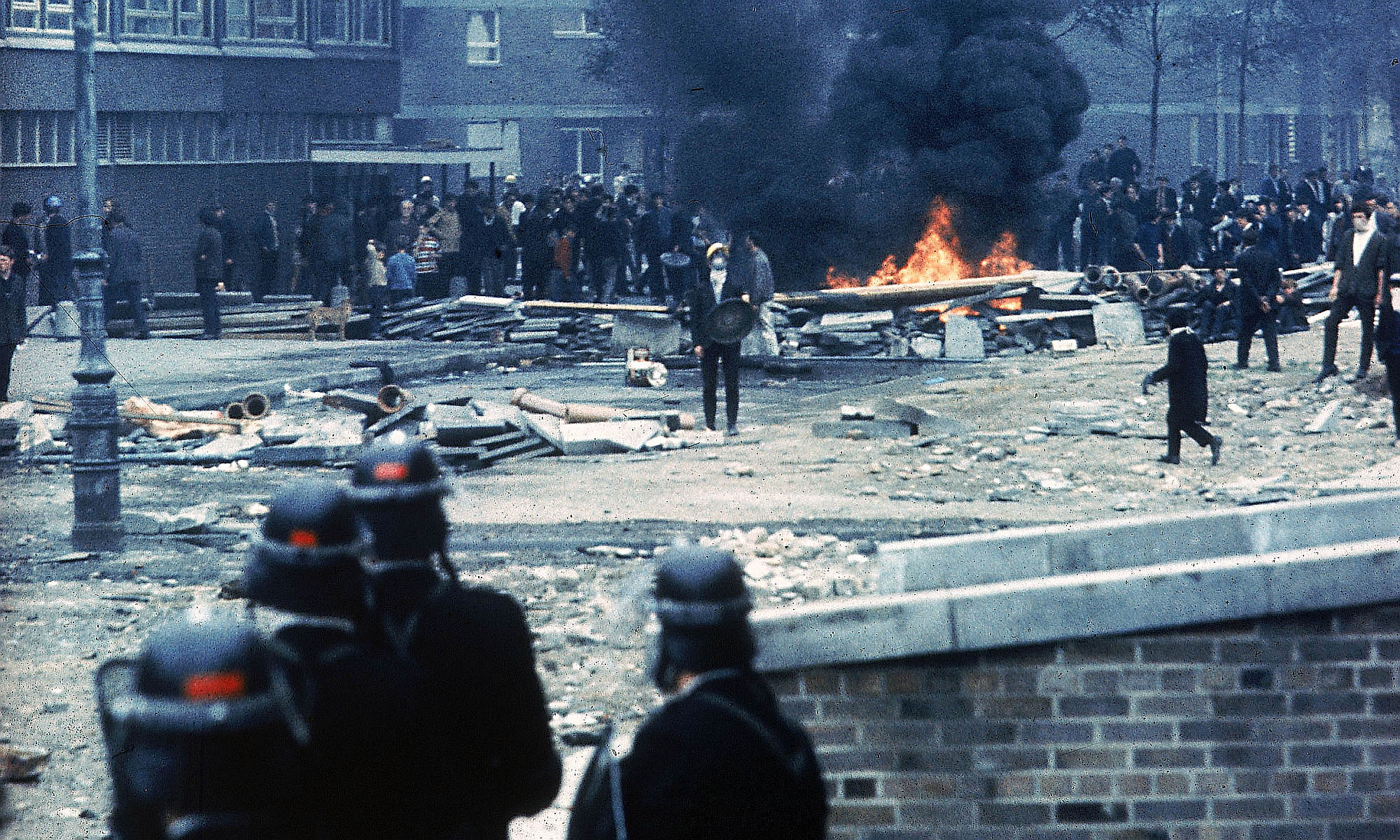 Police in riot gear watch on during protests in Londonderry, 12 August 1969.