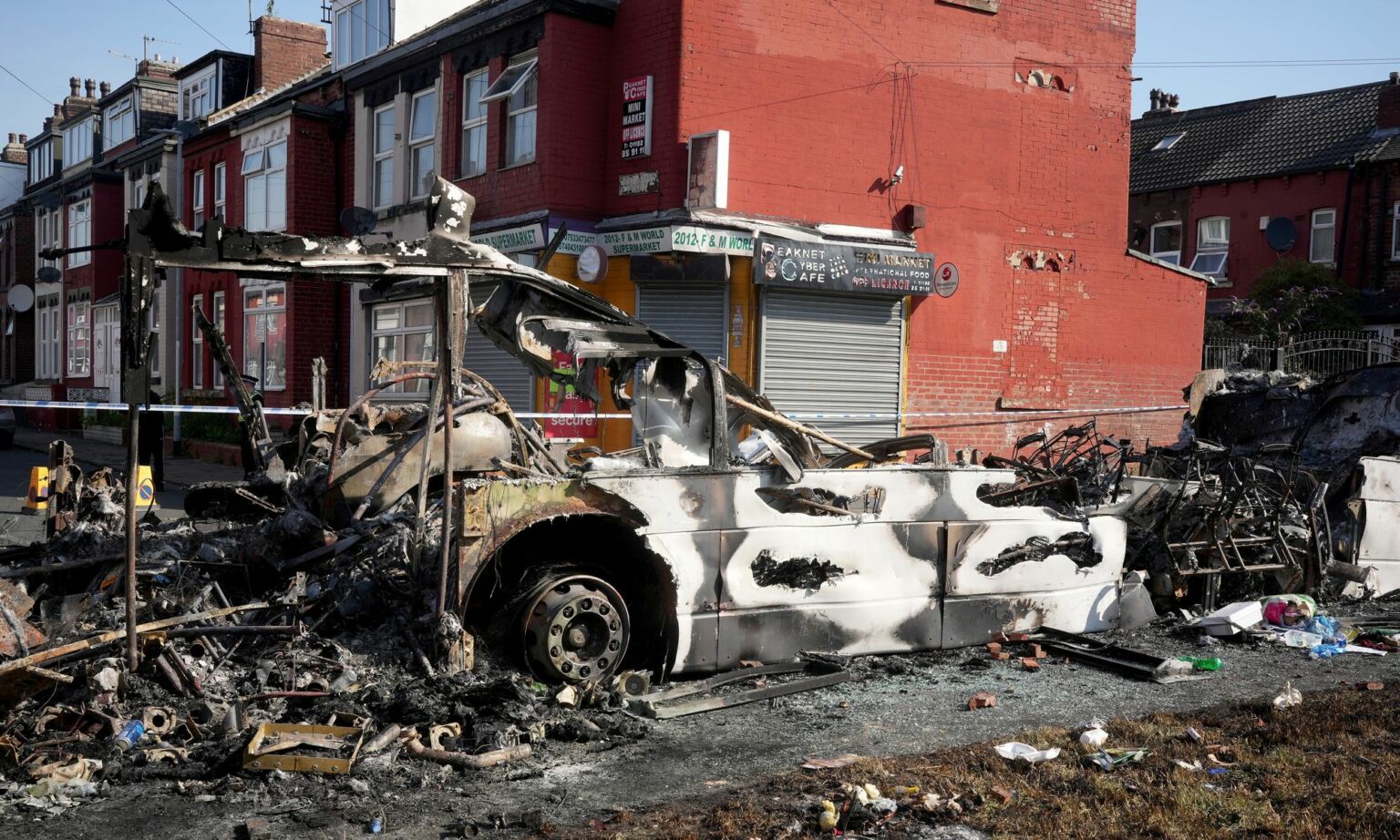 Police tape cordons off the remains of a burnt-out bus following riots in the Harehills area of Leeds, 19 July 2024.