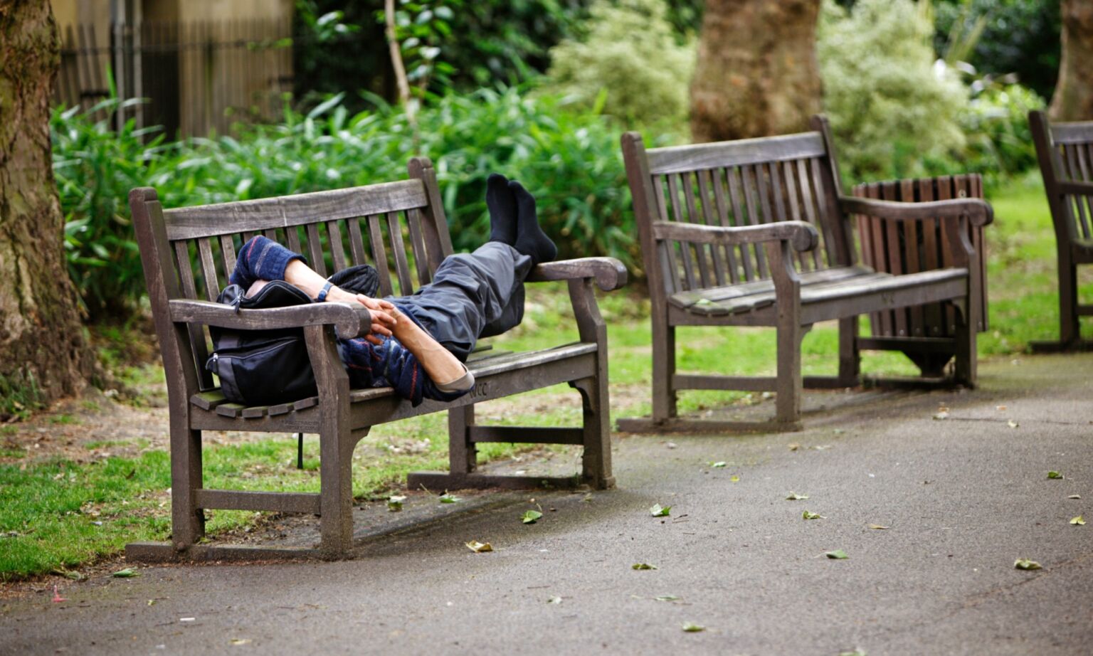 A man sleeping on a park bench in London.